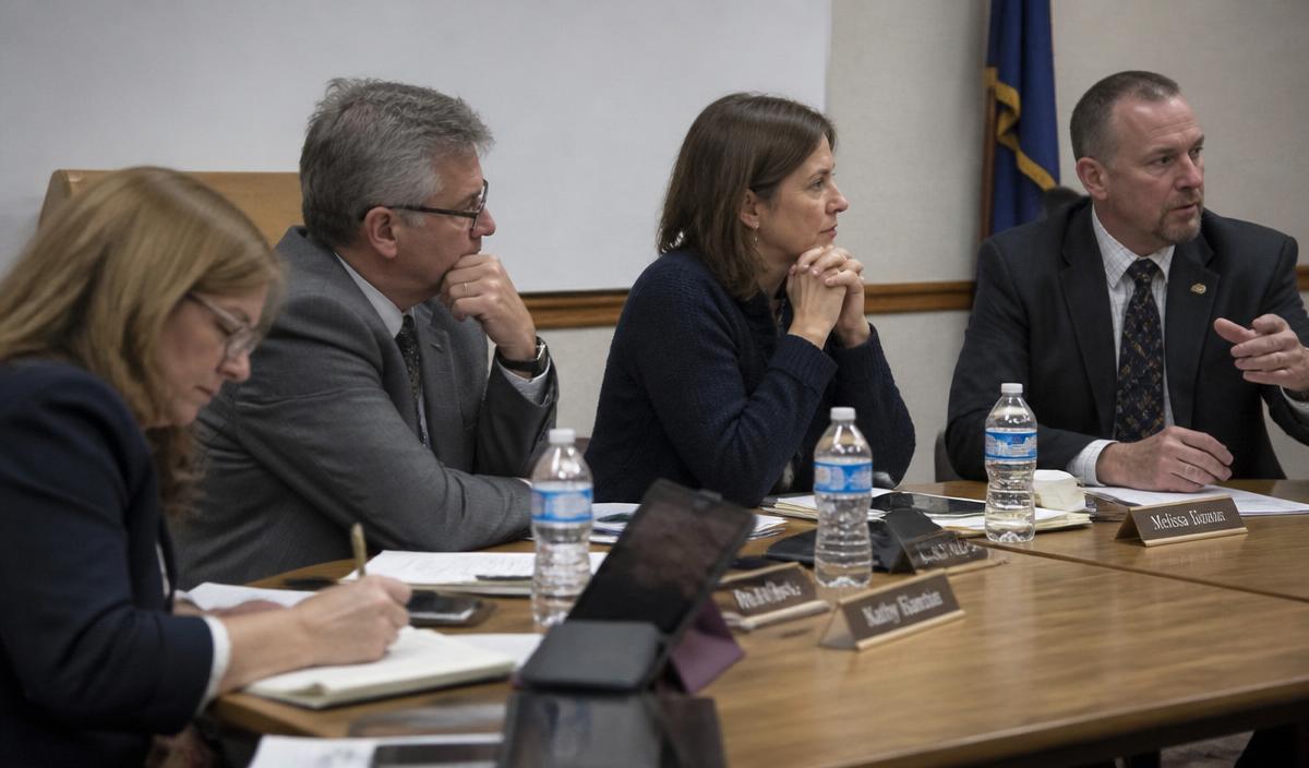 School board members seated at a meeting table, listening and taking notes.